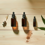 Trois flacons d'huile CBD différentes concentrations, flat-lay table en bois clair